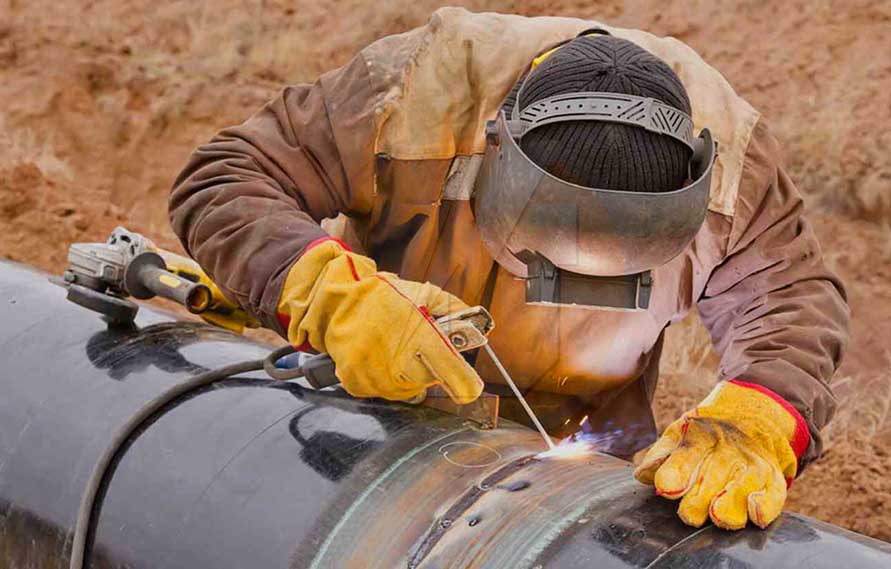 Professioneller Schweißer bei Schweißarbeiten an Öl und Gas Rohrleitungen